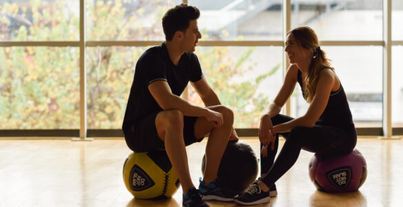 Man and Woman sitting with fitballs in the gym.