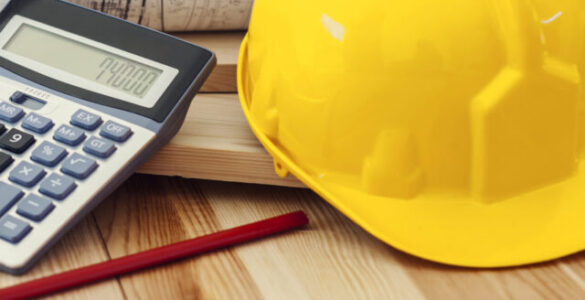 Yellow helmet with blueprints and calculator on wood