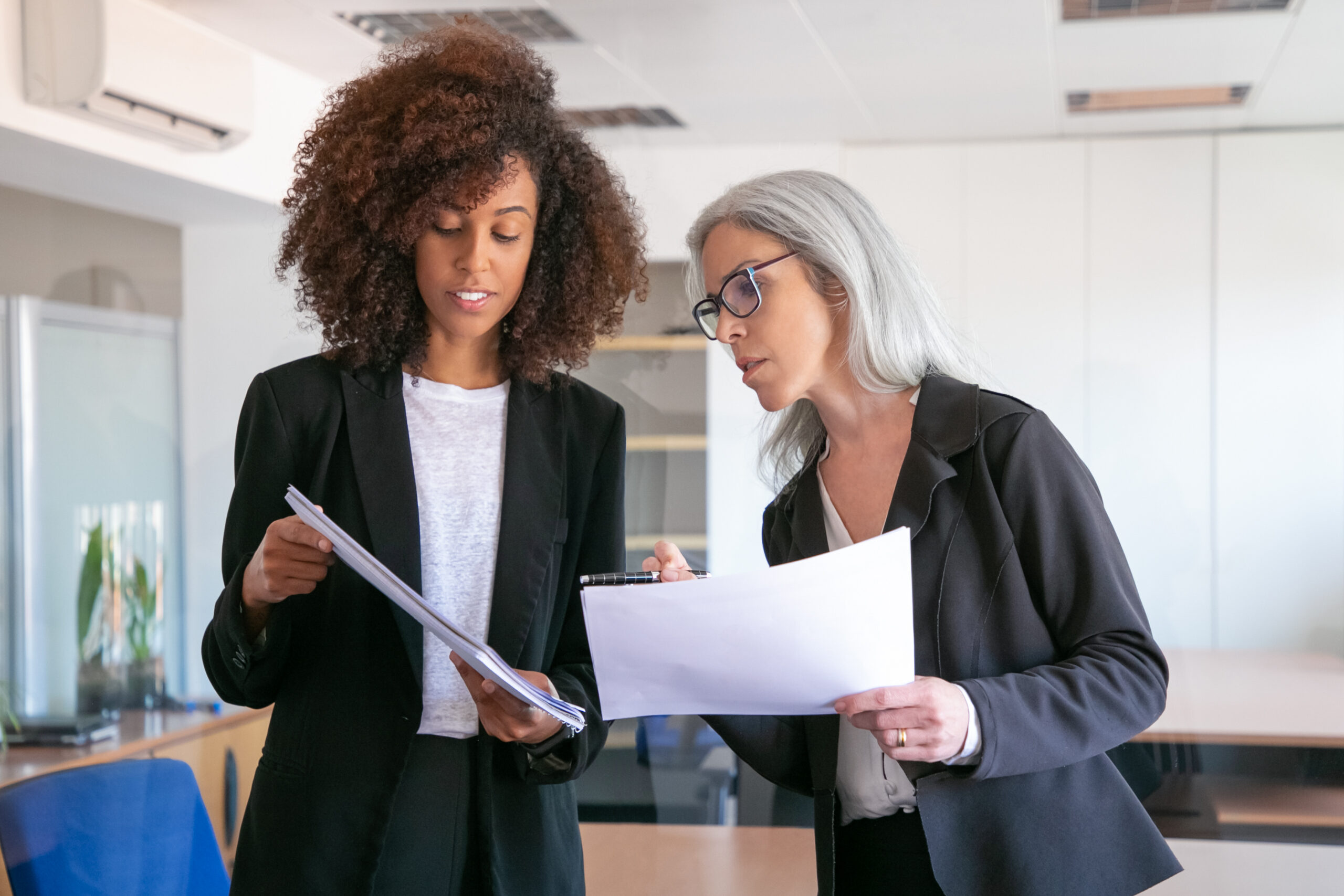 Content young manager showing document to adult colleague