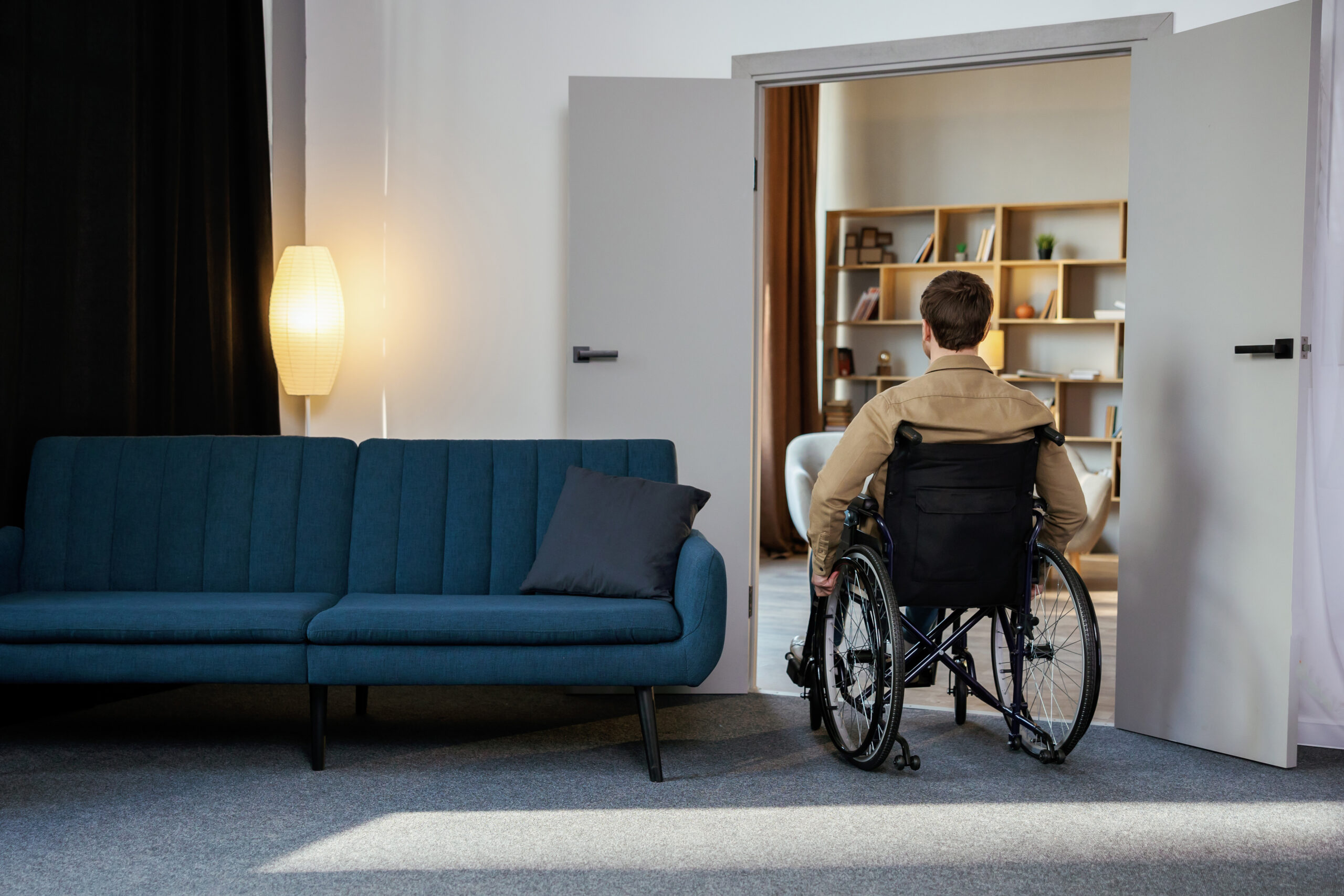 A handsome young man in a wheelchair moves around the apartment, getting used to a new life. Recovery after injury or ill lonely at home
