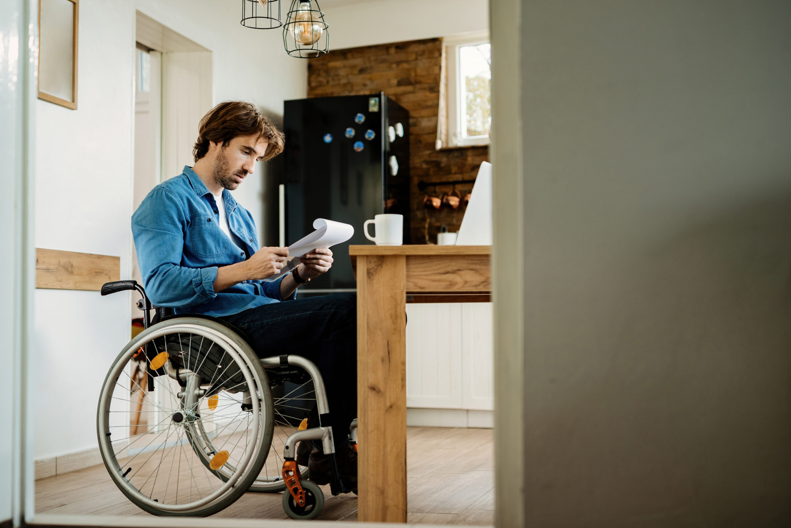 Young disabled businessman reading reports while working at home